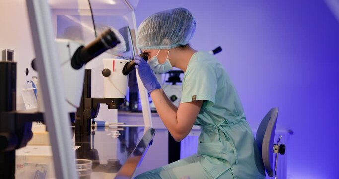 Embryologist performing an artificial fertilization of human egg at the laboratory using a microscope and specialized equipment. Embryologist Conducting Artificial Fertilization in Laboratory