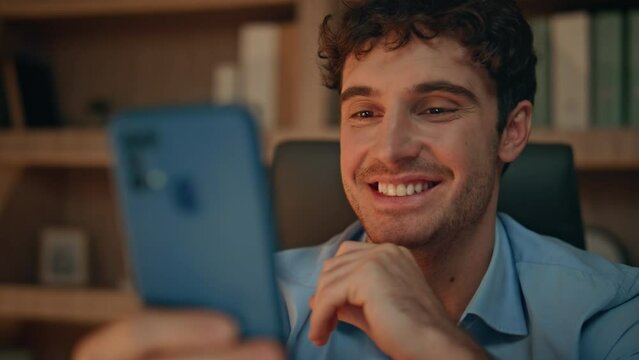 Happy employee looking mobile phone receiving notification at night home closeup