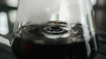 barista making a drip coffee, pouring hot water from kettle over a ground coffee powder