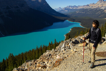 Hiker woman with hiking stick. On a clear sunny autumn day at beautiful Peyto Lake with turquoise...