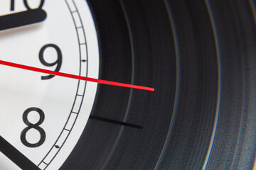 Clock vinyl record plate, arrow, backward time close-up.