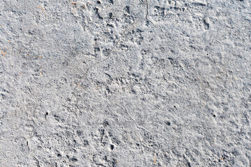 Texture of a rough, cracked and somewhat dirty cement wall.