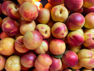 Pile of ripe freshly picked organic peaches. Pile of peach harvest. Healthy vegan raw snack. Clean eating concept. Cropped shot, background, top view.