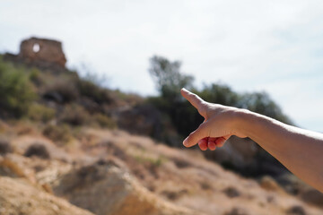 a child's hand pointing to a hilltop ruin