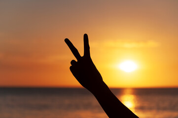 Fototapeta premium Hand with peace sign sunset background