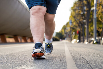 legs of a fat man jogging on the road, running in the street