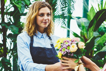 Professional female gardener selling fresh flowers grown on plant in own botanic...