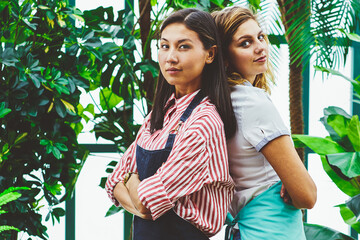 Half length portrait of confident female workers of botanic orangery back to back,serious florist...