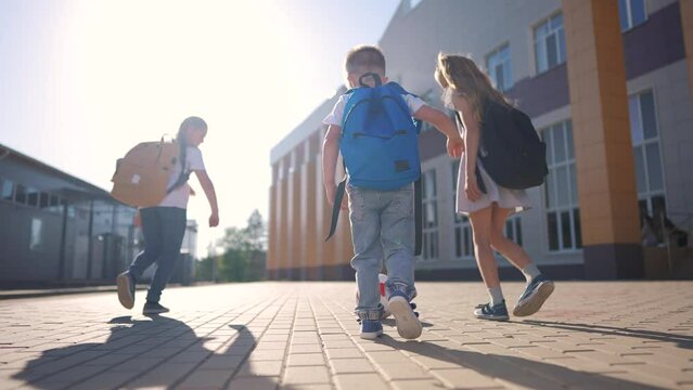 school children playing backpacks. happy a family kid dream school concept. children playing ball outdoors. a large group of lifestyle children with backpacks near the school playing soccer ball