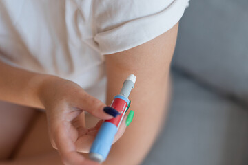 Girl gives herself an injection of anti diabetes in her arm at home. injectors dosing pen for...