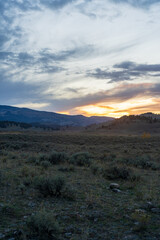 Sunset in the Lamar Valley in Yellowstone National Park in Montana and Wyoming on a beautiful fall evening. Sun sets over the mountains and sagebrush with a colorful sky illuminating the landscape.