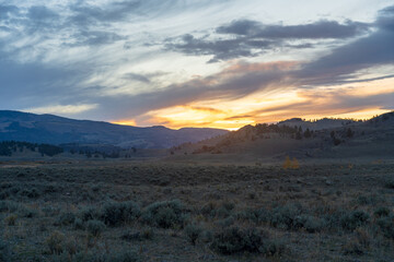 Sunset in the Lamar Valley in Yellowstone National Park in Montana and Wyoming on a beautiful fall evening. Sun sets over the mountains and sagebrush with a colorful sky illuminating the landscape.