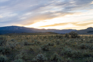 Sunset in the Lamar Valley in Yellowstone National Park in Montana and Wyoming on a beautiful fall evening. Sun sets over the mountains and sagebrush with a colorful sky illuminating the landscape.