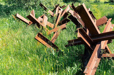 Rusty anti-tank hedgehogs among the thick green grass