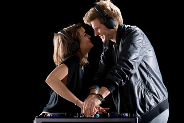 Two DJs share affectionate moment, headphones on