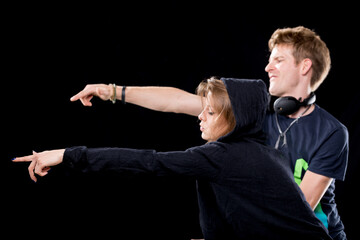 DJs smiling and pointing, lively performance, dark background