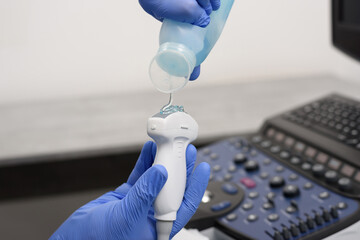 Probe for ultrasound diagnostics close-up. The doctor holds in his hands a transducer with a gel...