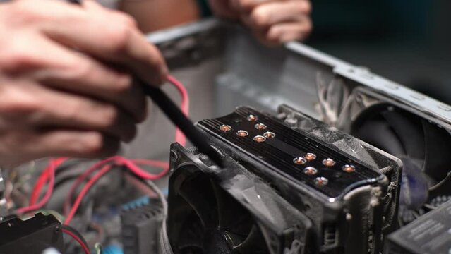 Unrecognizable male cleaning inside of PC case with equipment units from dust. Process cleaning old computer power supply from dust and dirt with brush. Concept of service for repair and cleaning.