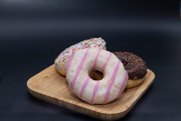 Donuts with icing and chocolate in a bamboo plate