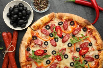 Tasty pizza and ingredients on black table, top view