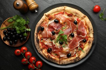 Tasty pizza with cured ham, olives, tomatoes and parsley on black table, top view