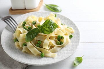 Delicious pasta with green peas served on white wooden table