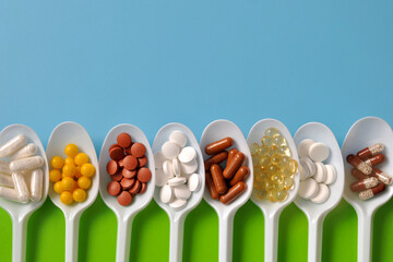 Tablets, capsules, dietary supplements, vitamins on spoons. Medical background