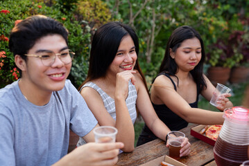 Young college students hanging out and having a nice picnic outdoors by the backyard enjoying pizza and drinks