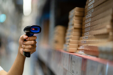 A person is holding a barcode scanner in a store. The shelves are full of boxes and the person is...
