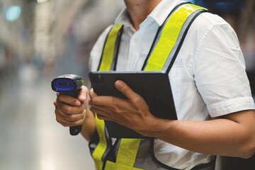 A man wearing a safety vest and holding a tablet and a barcode scanner. He is likely working in a...