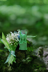 Shaman, forest spirit figurine and Lily of the valley flowers in forest, natural backdrop. Forest...