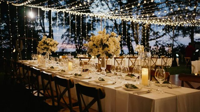 Dinner table setup sunset background. Close up decoration flowers candles Boho style. Romantic wedding reception party outdoor.
