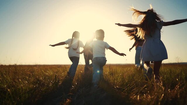 The children run play in the forest. happy family kid dream concept. The children running in the park silhouettes. children kid running across the field group in park silhouette at sunset lifestyle