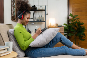 Obraz premium Cheerful young black woman excited using laptop computer on sofa at home, studying using laptop, reading and surfing the internet, receiving messages from friends, talking about weekend plans.