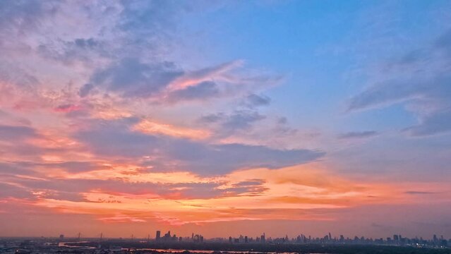 Time lapse interval sunset over modern office buildings in business district. Skyline cirrus cloudscape view of cityscape with disc sun sunlight and flare.