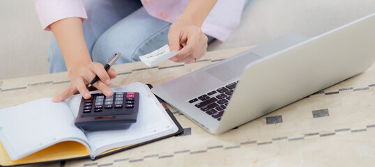 Closeup hands of woman calculating finance household with calculator on desk at home, girl checking bill for saving and planning expenses, debt and loan, tax and accounting, business and financial.