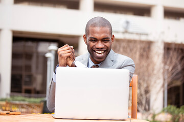 Thrilled businessman reading great news on his laptop computer celebrates success 