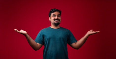 Happy positive Indian guy open both hands isolated on red colour background, Best offer concept...