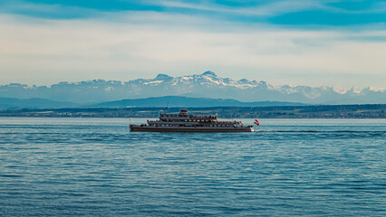 Alpine spring view with a ship and the alps in the background near Meersburg, Lake Bodensee, Baden-Württemberg, Germany