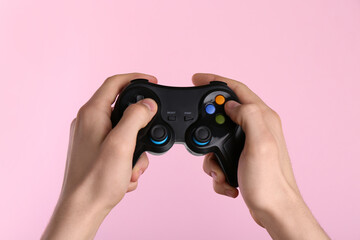 Man using wireless game controller on pink background, closeup