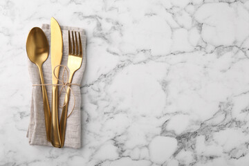 Set of stylish cutlery and napkin on white marble table, top view. Space for text