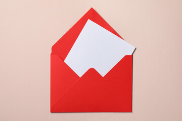 Letter envelope with card on beige background, top view