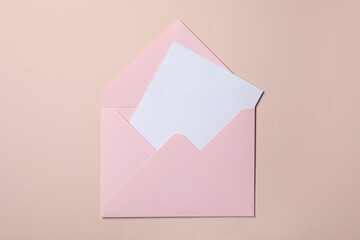 Letter envelope with card on beige background, top view