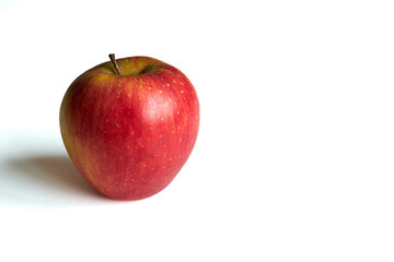 A vibrant, red apple is centered on a plain white background, illuminated by natural light. The apples surface is smooth with a slightly glossy sheen.