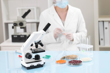 Quality control. Food inspector working in laboratory, focus on microscope and petri dishes with...