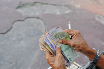 trader's hand holding Indonesian currency, calculate sales results