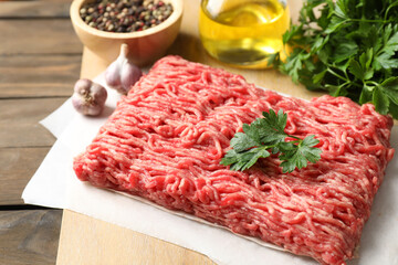 Raw ground meat, parsley and garlic on wooden table, closeup
