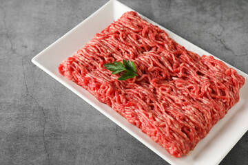 Raw ground meat and parsley on grey table