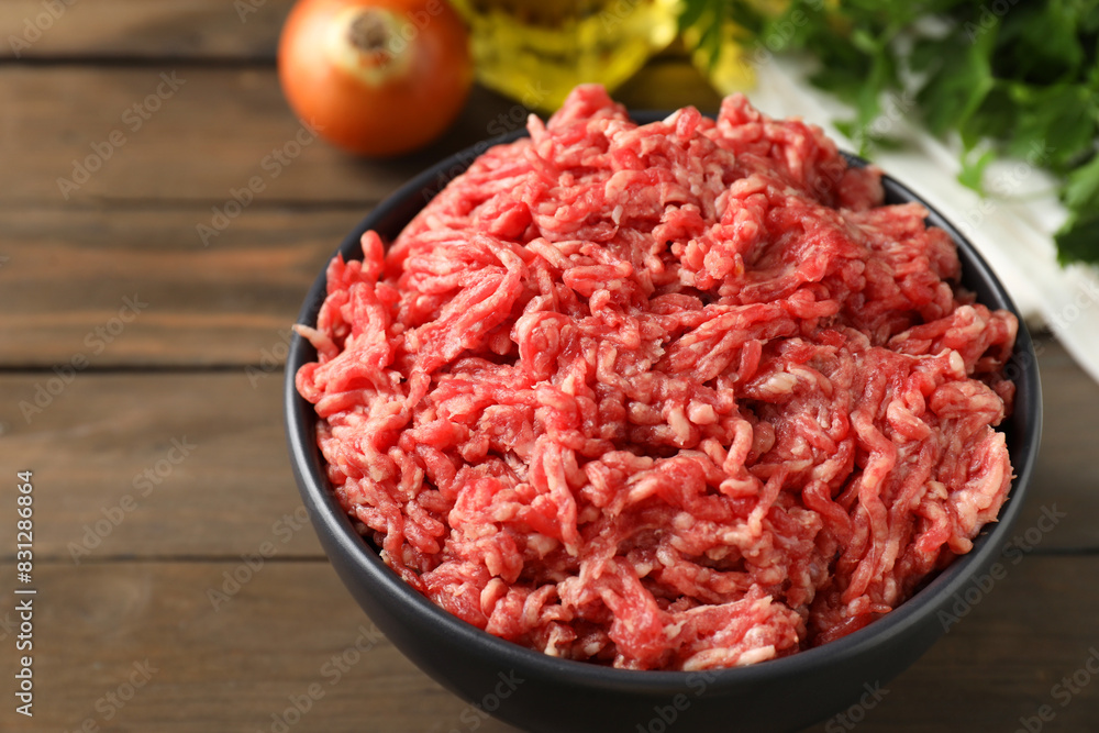 Wall mural raw ground meat in bowl on wooden table, closeup