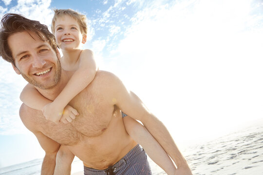 Father, boy and happy in beach with piggyback on holiday in summer, bonding and support in Miami. Parent, kid and smile or excited with fun at seaside on vacation, trip and travel on portrait